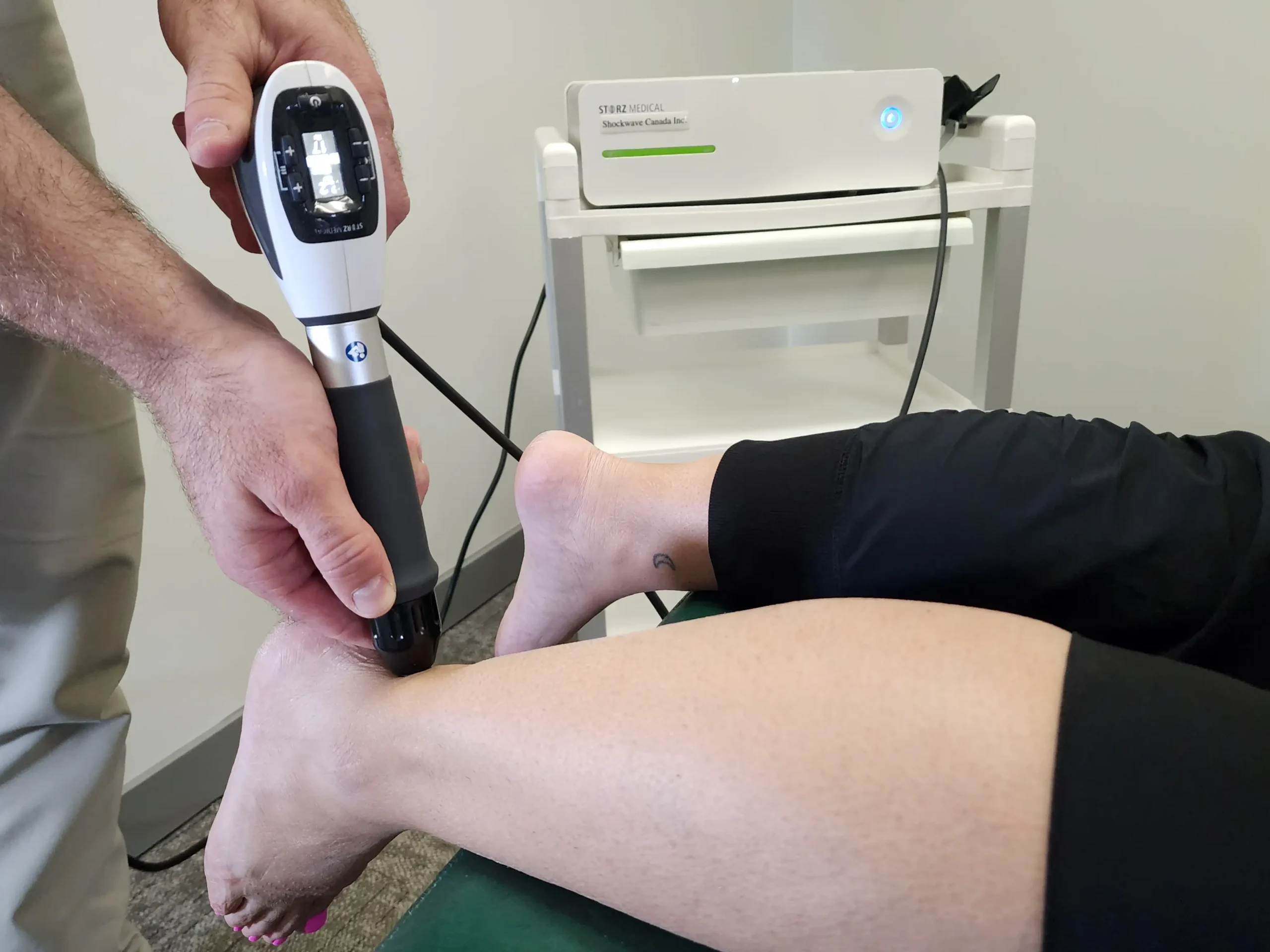 Chiropractor providing shockwave therapy in Edmonton to treat a patient’s Achilles tendon pain.